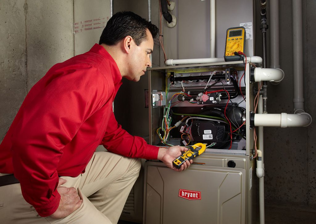 Heating and air conditioning technician servicing an indoor furnace in Chandler, AZ
