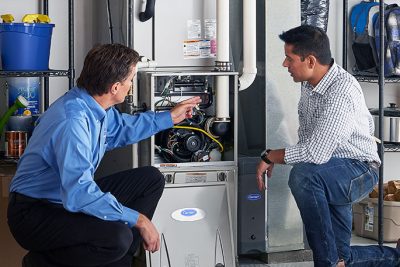 65df8c11f3e4c468cbd351a5_furnace repair vs replacement – Copy HVAC technician explaining furnace repair and maintenance to a homeowner in Chandler, AZ